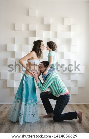 Man is kissing his pregnant wife's belly. Last months of pregnancy. Pregnant woman with husband and little boy . Happy family waiting for a second child. Second pregnancy, maternity concept.