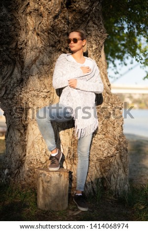 Young woman leaning on a tree and posing for a camera 
