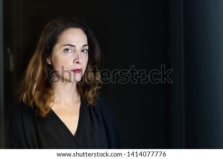 Portrait of a woman 48 years old, looking serious, pensive, isolated over black.