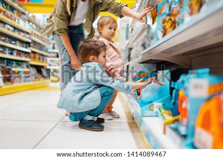 Mother with her children at the shelf in store Royalty-Free Stock Photo #1414089467