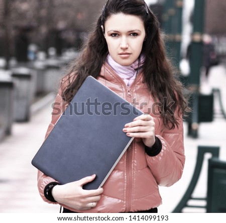 young woman with laptop on background of a winter city