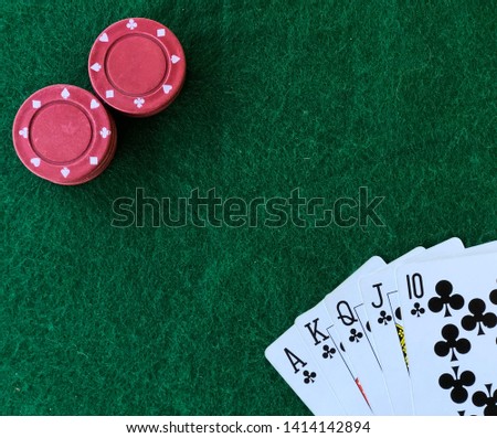 Royal flush poker hand on green gambling table. Stacked red betting chips are visible.