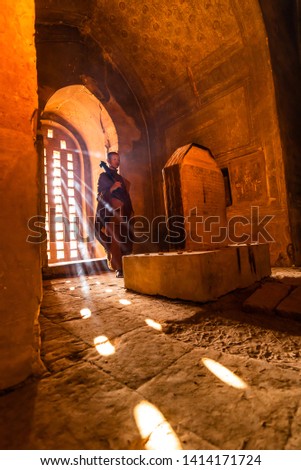 A Monks of Buddhism come to visit and respect Ancient buddha statue at Temple a Buddhist temple located in Bagan, Myanmar,with sunlight ray background