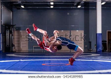 The concept of fair wrestling. Two greco-roman  wrestlers in red and blue uniform wrestling   on a wrestling carpet in the gym.The concept of fair wrestling Royalty-Free Stock Photo #1414189985