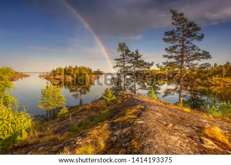 Scenic view of uninhabited islands. Epic sky. Colored rainbow. Sunny clear day on the water. Yellow moss covers the rocks. Magical northern nature. National park. Ladoga lake. Republic of Karelia