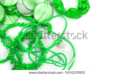 Green beads and headphones on a blue background. Accessory