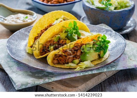 Smoky Mexican pork and bean tacos with lettuce and avocado salad