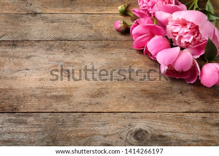 Fragrant peonies on wooden table, top view with space for text. Beautiful spring flowers