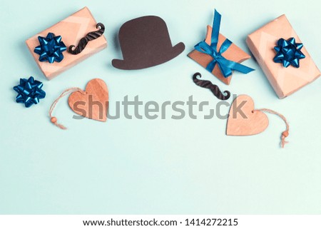 Fathers day concept with gift boxes, mustache and paper hat on blue background. Flat lay, top view, copy space.
