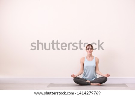 Young woman meditating near light wall, space for text. Zen concept Royalty-Free Stock Photo #1414279769