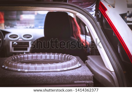 Giant Subwoofer Speaker in the Trunk, Red Hair Woman in the Front Seat. Royalty-Free Stock Photo #1414362377