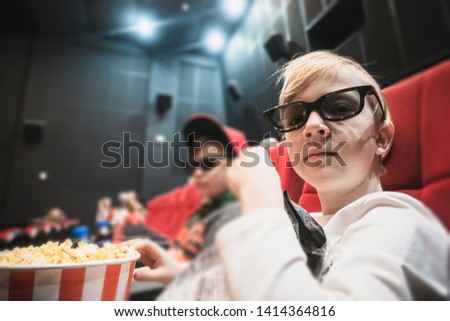 Boy at the cinema in stereo glasses and popcorn