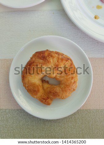 Croissant in a white plate placed on a wooden table.