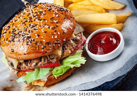 Close up view on fresh big burger served with sauce and French fries. Traditional american fast food. Juicy cheeseburger with lettuce, pickled cucumber, tomato. Copy space