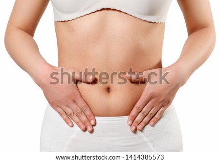 Concept of early term of pregnancy. Close up photo of woman's abdomen and belly button, she is touching her slim stomach with two hands. isolated on white background