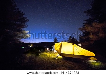 Family tent with rigid steel poles on camping ground under Starry sky with Milky Way