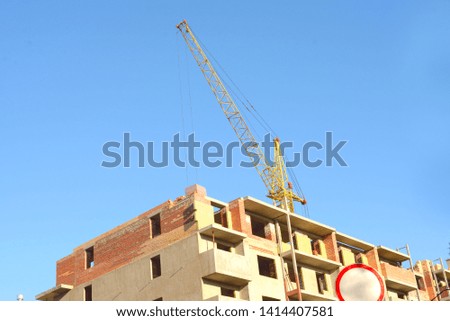 bandoned construction of a multi-storey brick house. Construction crane and brick house. No-entry sign.
