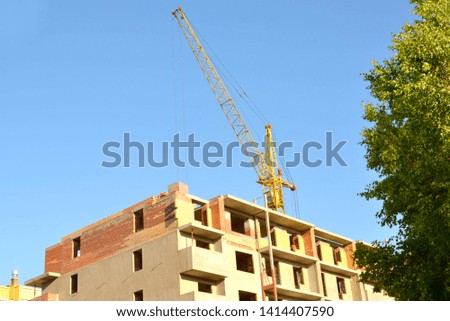 bandoned construction of a multi-storey brick house. Construction crane and brick house. No-entry sign.