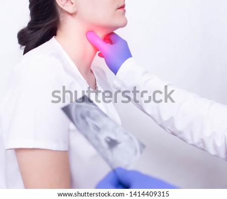 A specialist doctor diagnoses a girl s sore throat by palpating for the presence of inflammation and swelling, sore throat and tonsillitis of the throat Royalty-Free Stock Photo #1414409315