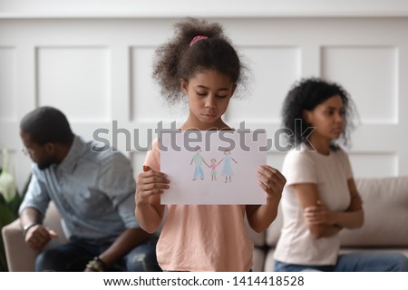 Sad african american school child girl holding family picture drawing feeling upset about parents divorce, innocent sensitive little kid suffer from trauma offended by fights conflicts shared custody