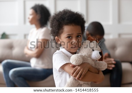 Portrait of upset little african child boy holding toy looking at camera, sad sensitive small mixed race kid feel lonely hurt suffer from family conflicts fights, parents divorce, children custody Royalty-Free Stock Photo #1414418555
