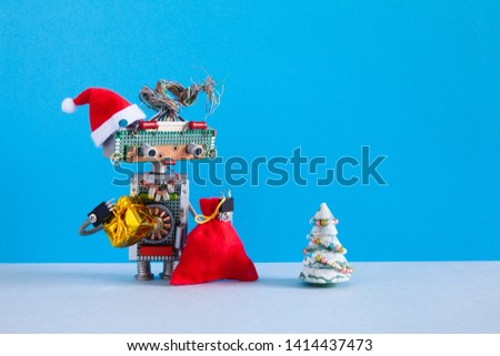 Romantic female robot Santa Claus looking at christmas tree. Creative design robotic toy with Santa hat, red bag of gifts on blue gray background. Xmas greeting poster. copy space