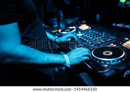 DJ mixing tracks on a mixer in a nightclub Royalty-Free Stock Photo #1414466330