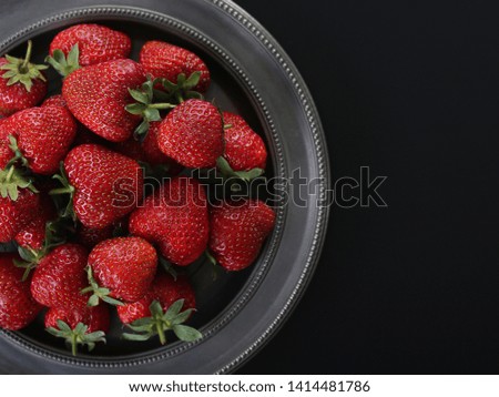 Strawberries on tin plate on black background. Top view