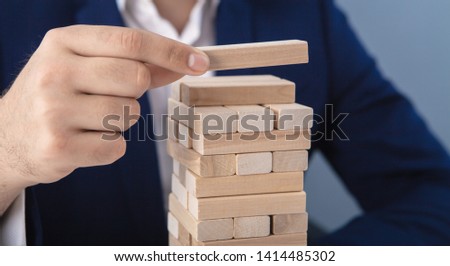 a businessman makes a pyramid with empty wooden cubes; business concept