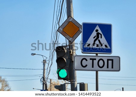 Traffic light with three colors and a sign with the inscription stop in Russian and blue sky with branch of tree in the background