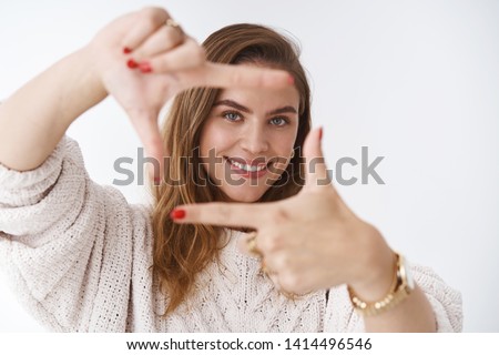 Creative good-looking woman using imagination picturing new appartment design how capture you making finger frame looking through curious delighted standing amused happy, smiling white background