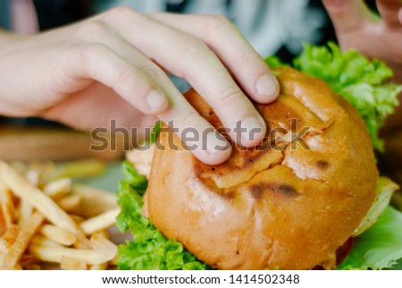 Man in a restaurant eating a hamburger, he is hungry and having a good bite. Burger dinner