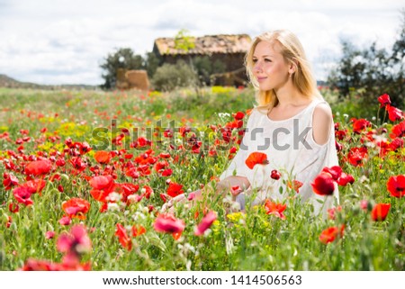 Beautiful young female  in white dress  in poppy field of wild flowers outdoor