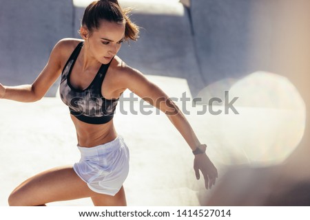 Fit young woman running in morning. Health conscious woman doing running workout outdoors. Royalty-Free Stock Photo #1414527014