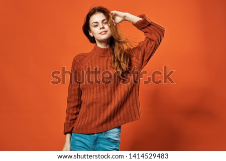Woman in orange sweater and jeans, cropped look                     