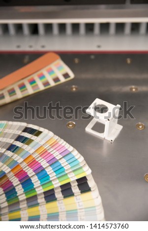 Press color management. Cmyk stripe loupe and color palette on the guillotine cutter background.