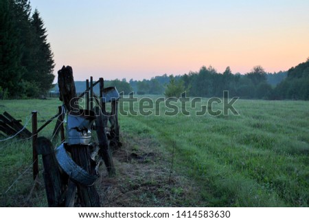 View of the old wooden fence on the outskirts of the village at dawn.