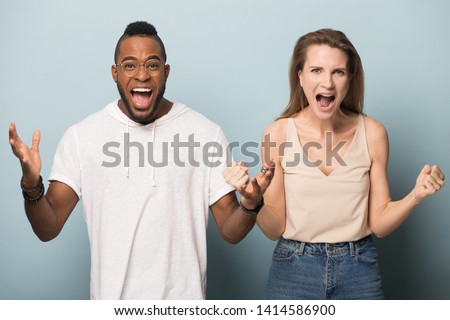 Young happy african american man and smiling excited caucasian woman screaming, shouting, two biracial people celebrating success, online lottery win, unbelievable offer, big sale, studio background.