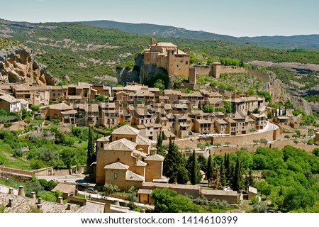 Panoramic view from above on the houses of medieval village Alquezar at daytime. Part of the Sierra de Guara Natural Park. Comarca Somontano de Barbastro, Huesca province, Aragon region, Spain.     Royalty-Free Stock Photo #1414610399