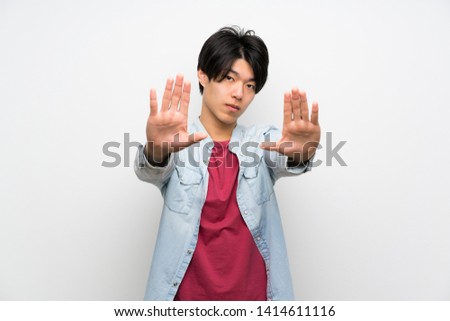 Asian man on isolated white background making stop gesture and disappointed
