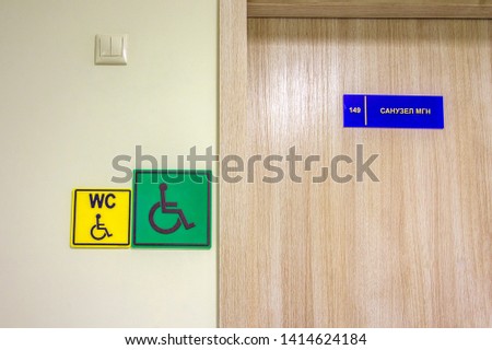 plate is acrylic. Door sign, doorplate hangs on light gray wooden. Number. Interior of school, kindergarten, institute, public. Inscription WC, disabled, bathroom MGN (people with limited mobility) 