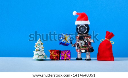 Robotic Santa Claus Christmas New year invitation poster background. Black head robot Santa red hat. Toy pine tree, a bag of gifts on blue wall background, copy text
