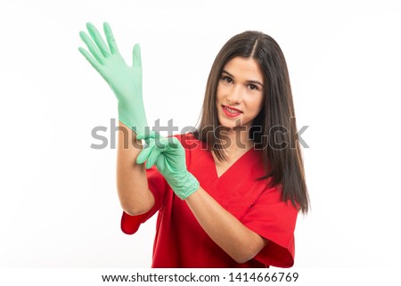 Portrait of beautiful nurse wearing scrubs showing silence gesture isolated on white background