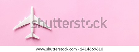 Top view of white model plane, airplane toy on pink pastel background. Flat lay with copy space. Trip or travel banner.