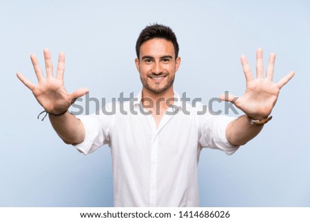 Handsome young man over isolated blue background counting ten with fingers