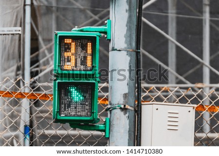 Pedestrian Traffic light in Taiwan showing green light and timer with construction site in the background