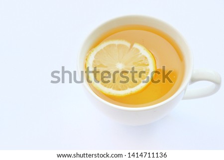  Tea  is in a white glass,there is a small piece of lemon in the glass. placed in the center of the picture, arranged with light and has a white background.