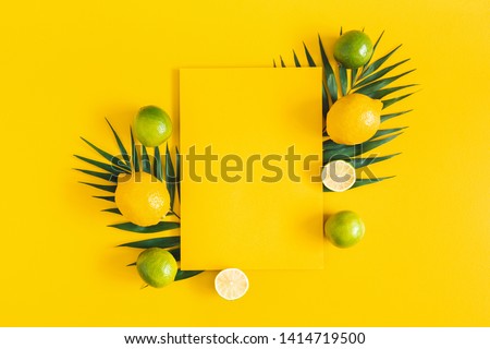 Summer composition. Tropical palm leaves, citrus fruits, yellow paper blank on yellow background. Summer concept. Flat lay, top view, copy space