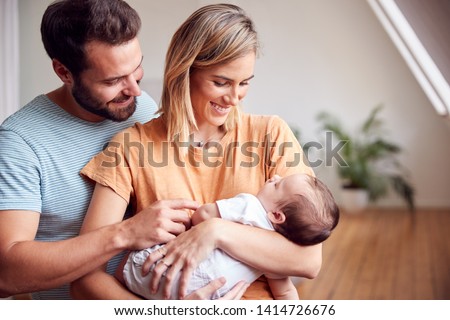 Loving Parents Holding Newborn Baby At Home In Loft Apartment Royalty-Free Stock Photo #1414726676