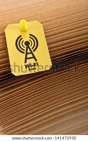 Sing of a wi-fi zone in yellow label on a books sheets.Modern technology that helps us concept shot/Wi-fi zone label